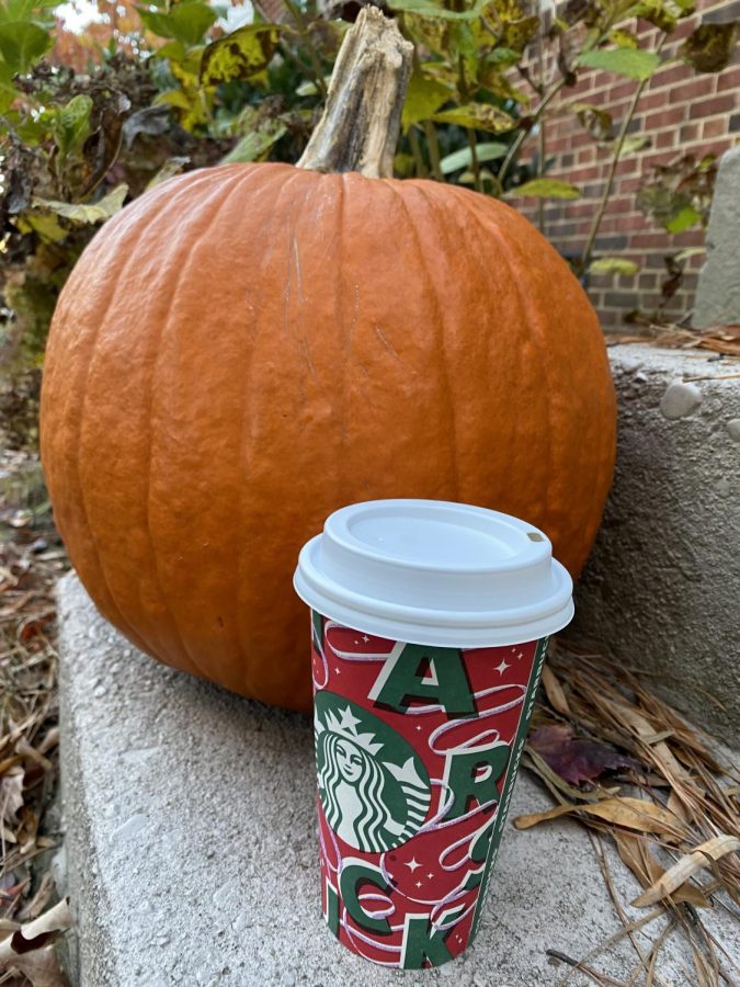 A festive Pumpkin spice latte next to a round pumpkin.