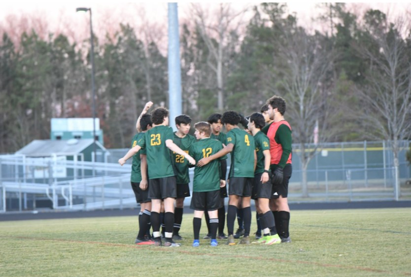 The Varsity Boys Soccer team huddles before an early season match. 