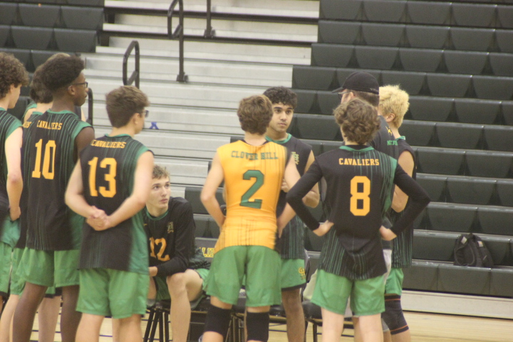 The boys volleyball team discusses the game during a break in play.
