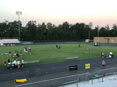 Students watch the sunrise on the football field.