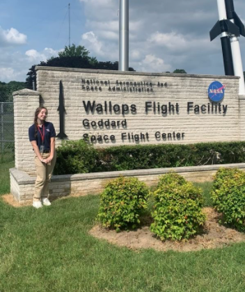 Stone stands in front of the sign at NASAs Wallops Flight Facility during the VSCS summer academy.