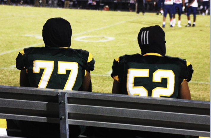 Junior CJ Brooks (#77) and senior Jayden Anderson (#52) sit on the bench following during an Cavalier offensive possesion.