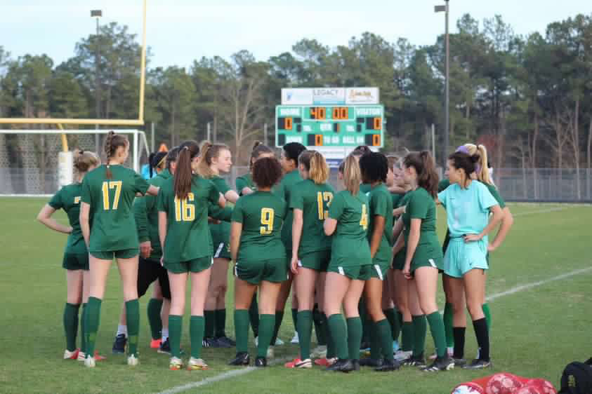The girls soccer team huddles around their team captains before an 8-1 win over the Manchester Lancers.