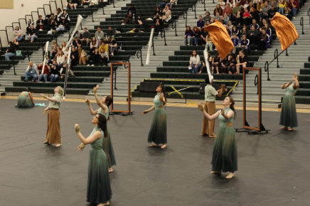 The winter guard throws their flags into the air during their performance.