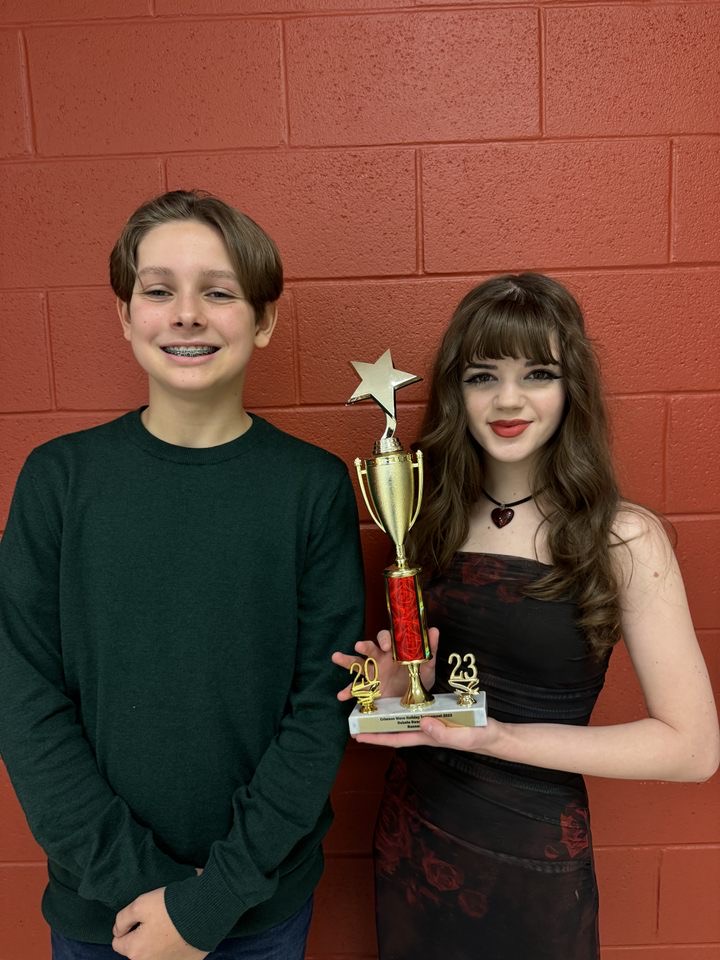Evan Learn (left) and Julia Herald (right) standing with the debate team trophy