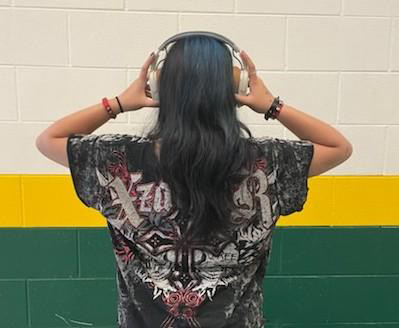 Student facing the wall with their hands over headphones that are on their head.
