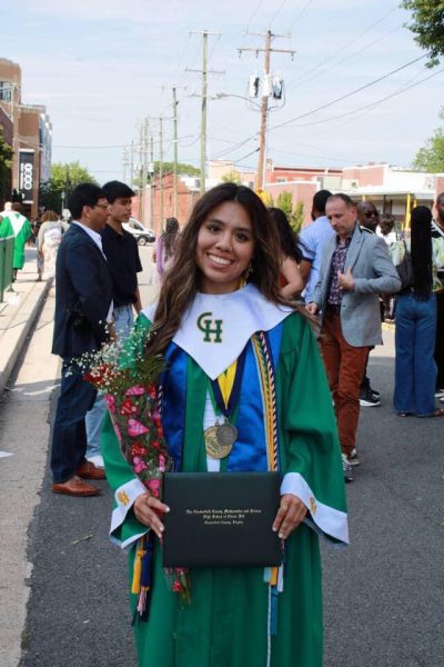 Vargas Mendoza posing for a picture after graduation wearing her gown and holding her diploma and flowers.