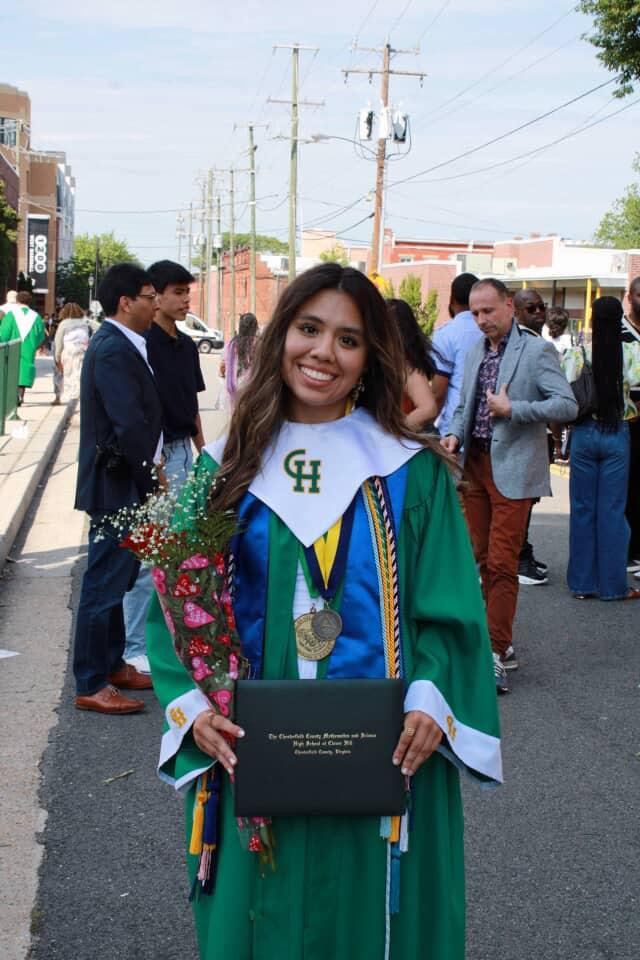 Vargas Mendoza posing for a picture after graduation wearing her gown and holding her diploma and flowers.