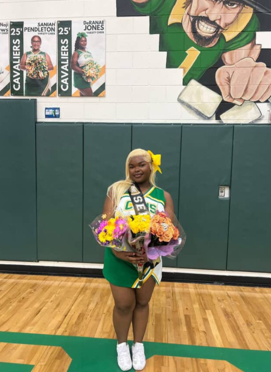 DeRanae Jones poses in her cheer uniform holding bouquets