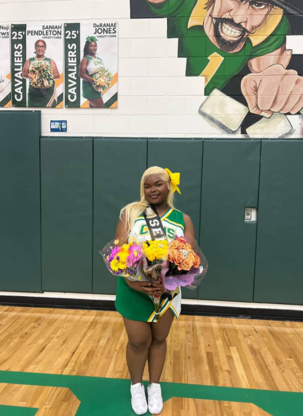 DeRanae Jones poses in her cheer uniform holding bouquets